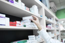 closeup view of pharmacist hand taking medicine box from the shelf in drug store